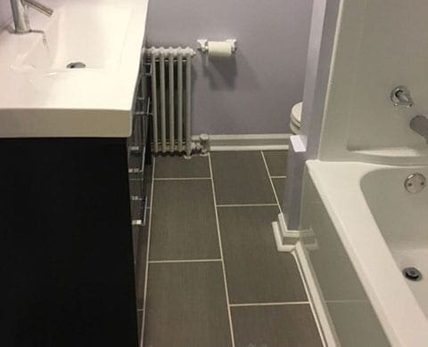 Bathroom with dark gray rectangular tile flooring and light gray grout.